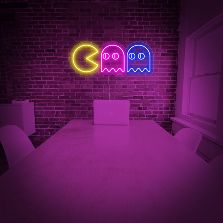 Insegna al neon LED con Pac-Man giallo e due fantasmi colorati su muro di mattoni