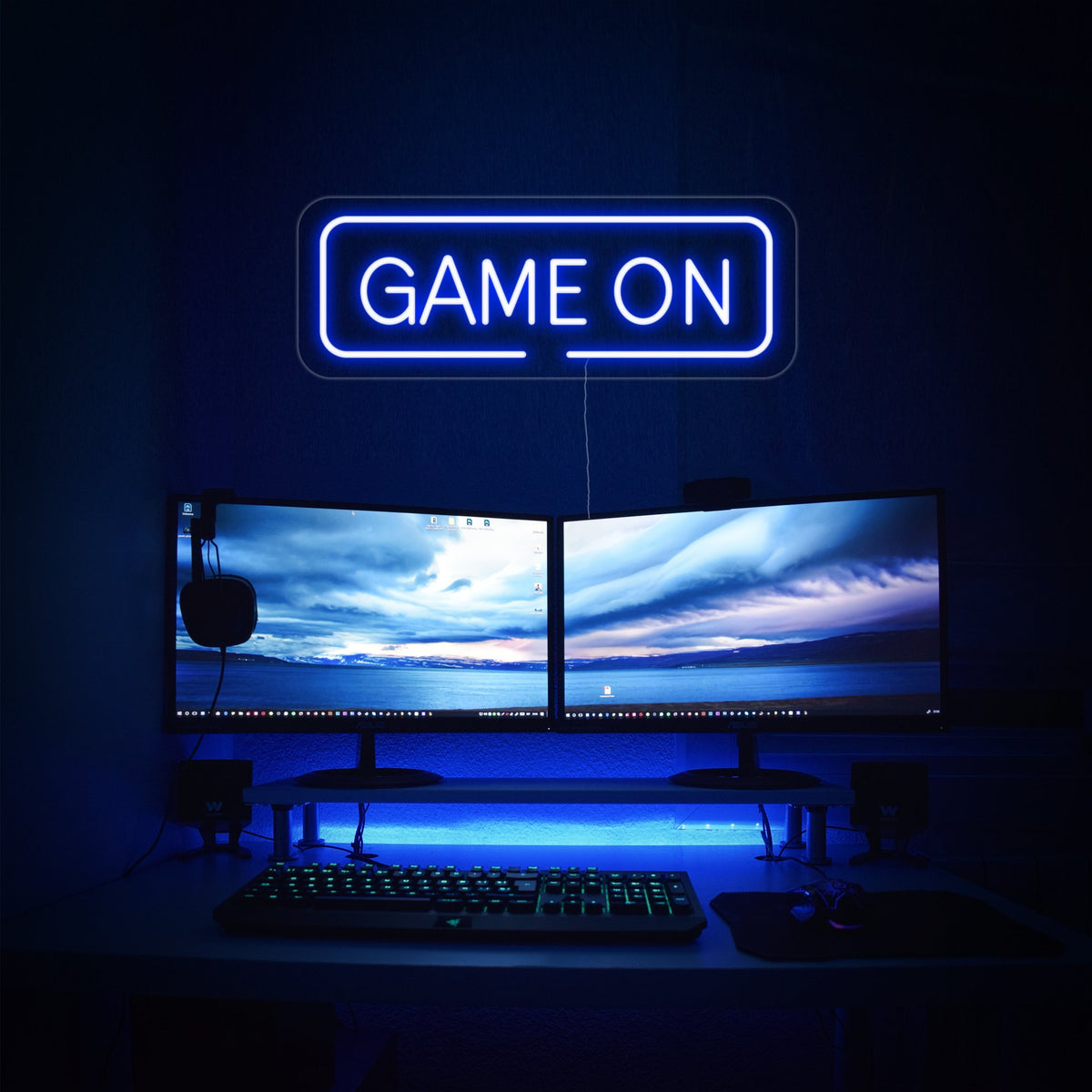 Insegna al neon LED blu GAME ON sopra doppio monitor in sala giochi